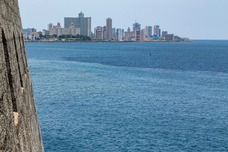 El mar visto desde un muro de piedra de una fortaleza, con la ciudad de La Habana al fondo