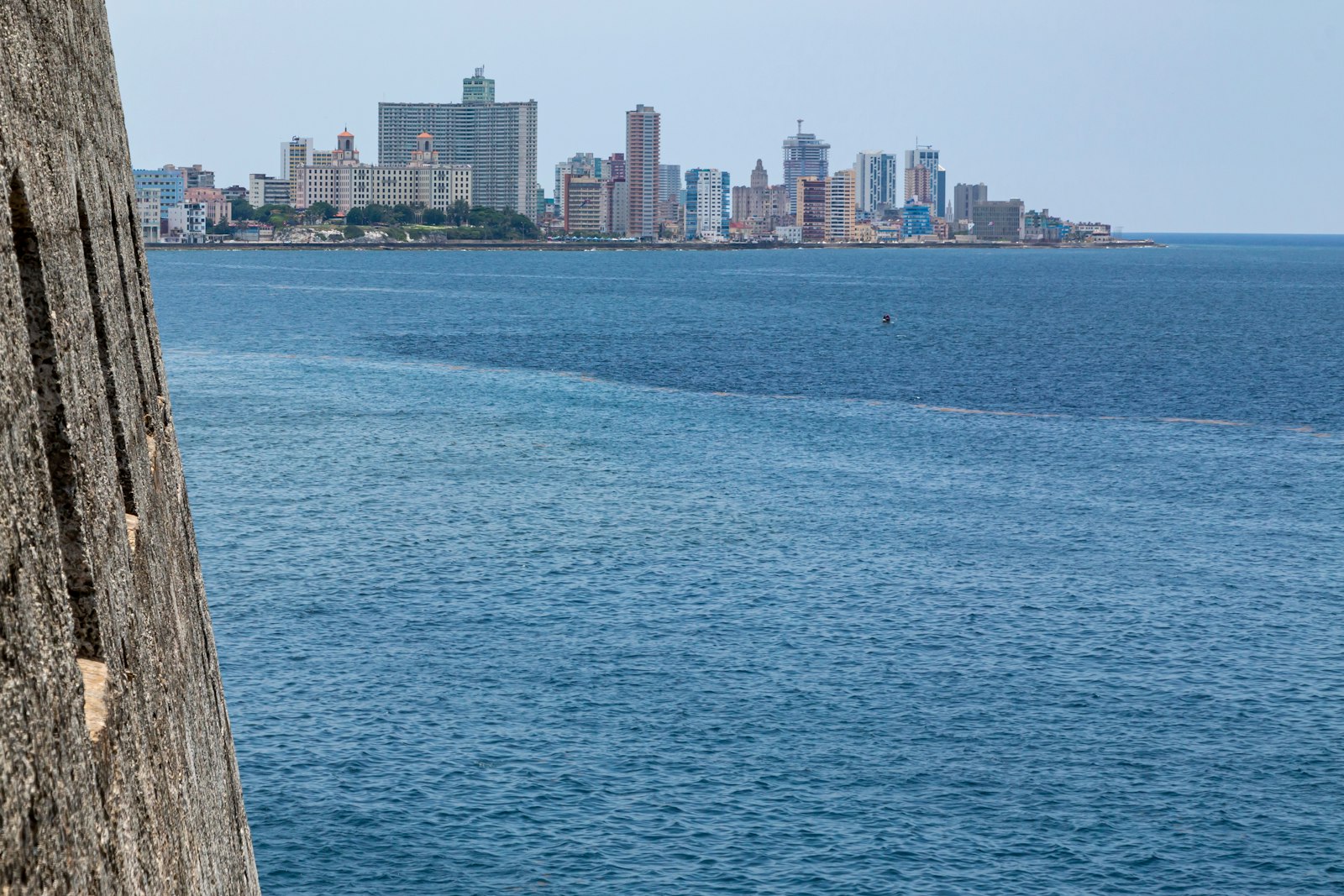 El mar visto desde un muro de piedra de una fortaleza, con la ciudad de La Habana al fondo