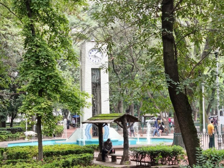 Reloj público en un parque con árboles