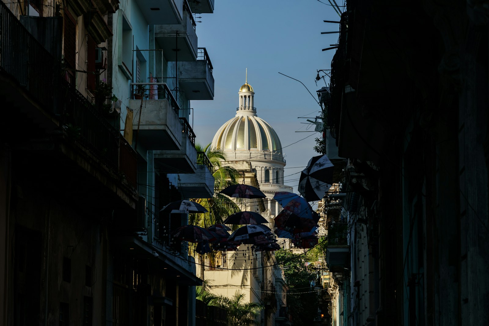 Cúpula blanca del Capitolio de La Habana iluminada de noche al fondo de una calle