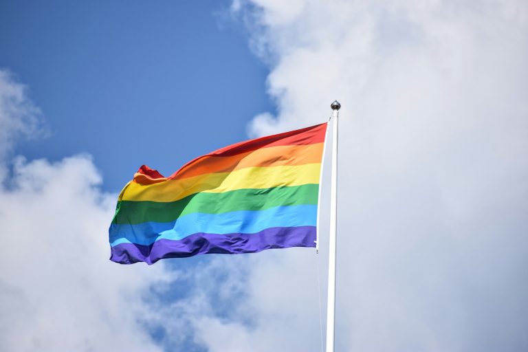 Bandera arcoíris ondeando en lo alto contra el cielo