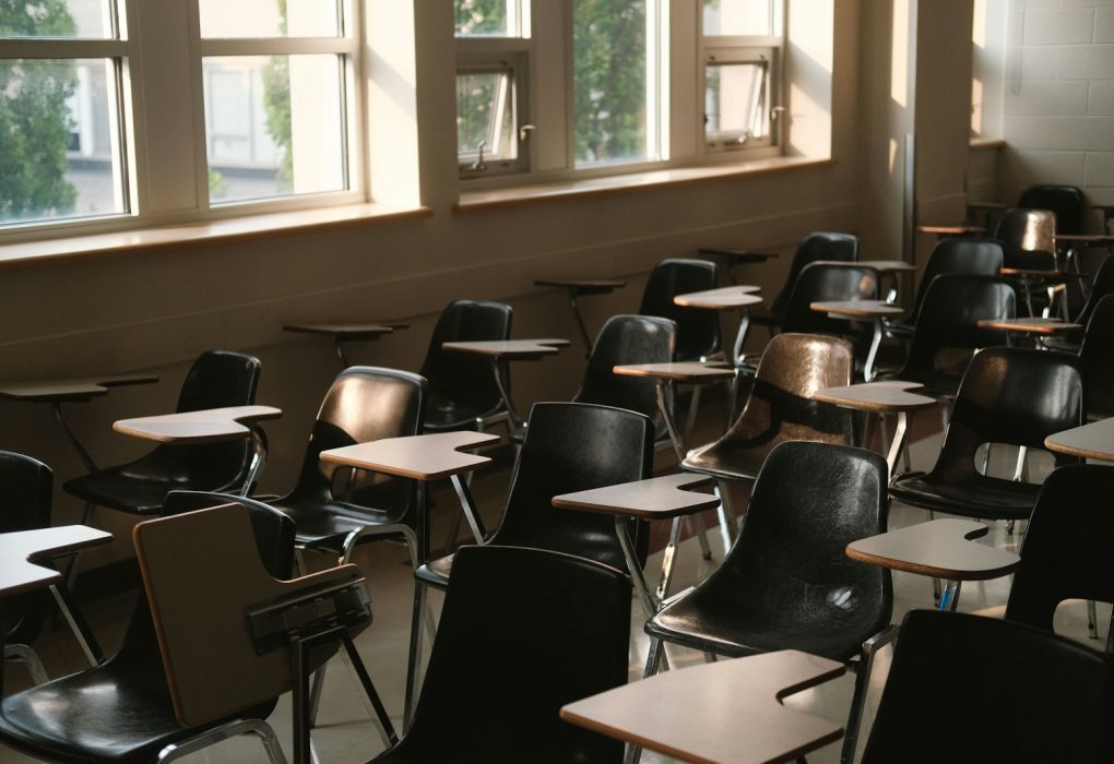 Aula vacía con pupitres y sillas junto a las ventanas