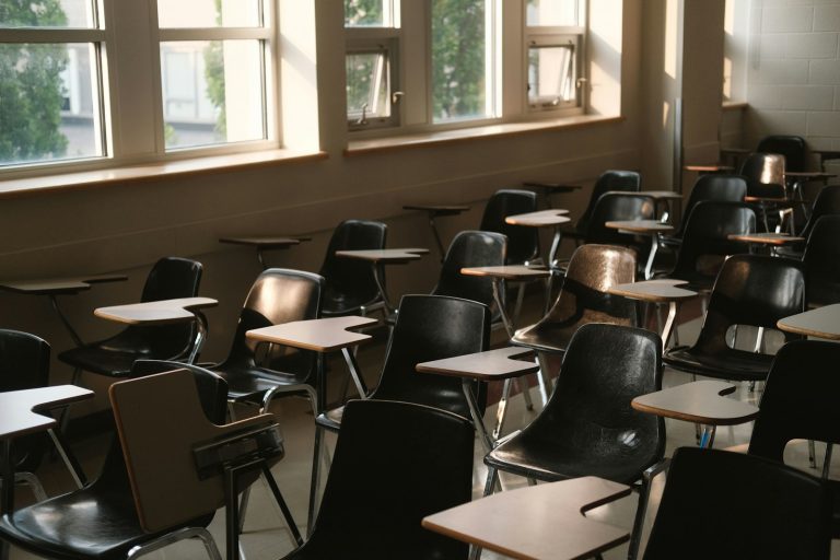 Aula vacía con pupitres y sillas junto a las ventanas