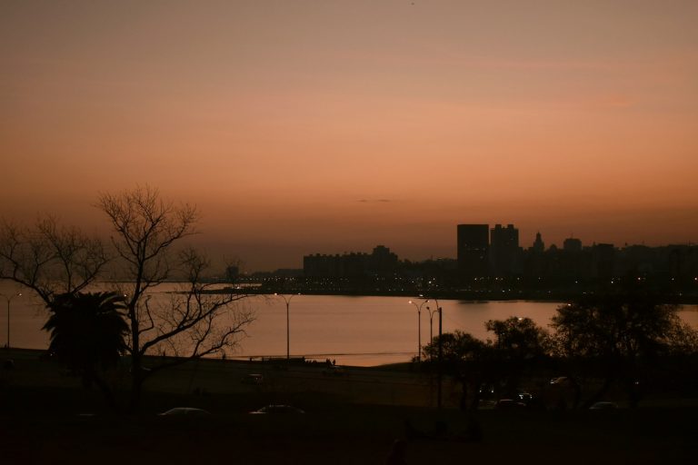 Atardecer sobre el agua con el perfil de edificios de la rambla de Montevideo
