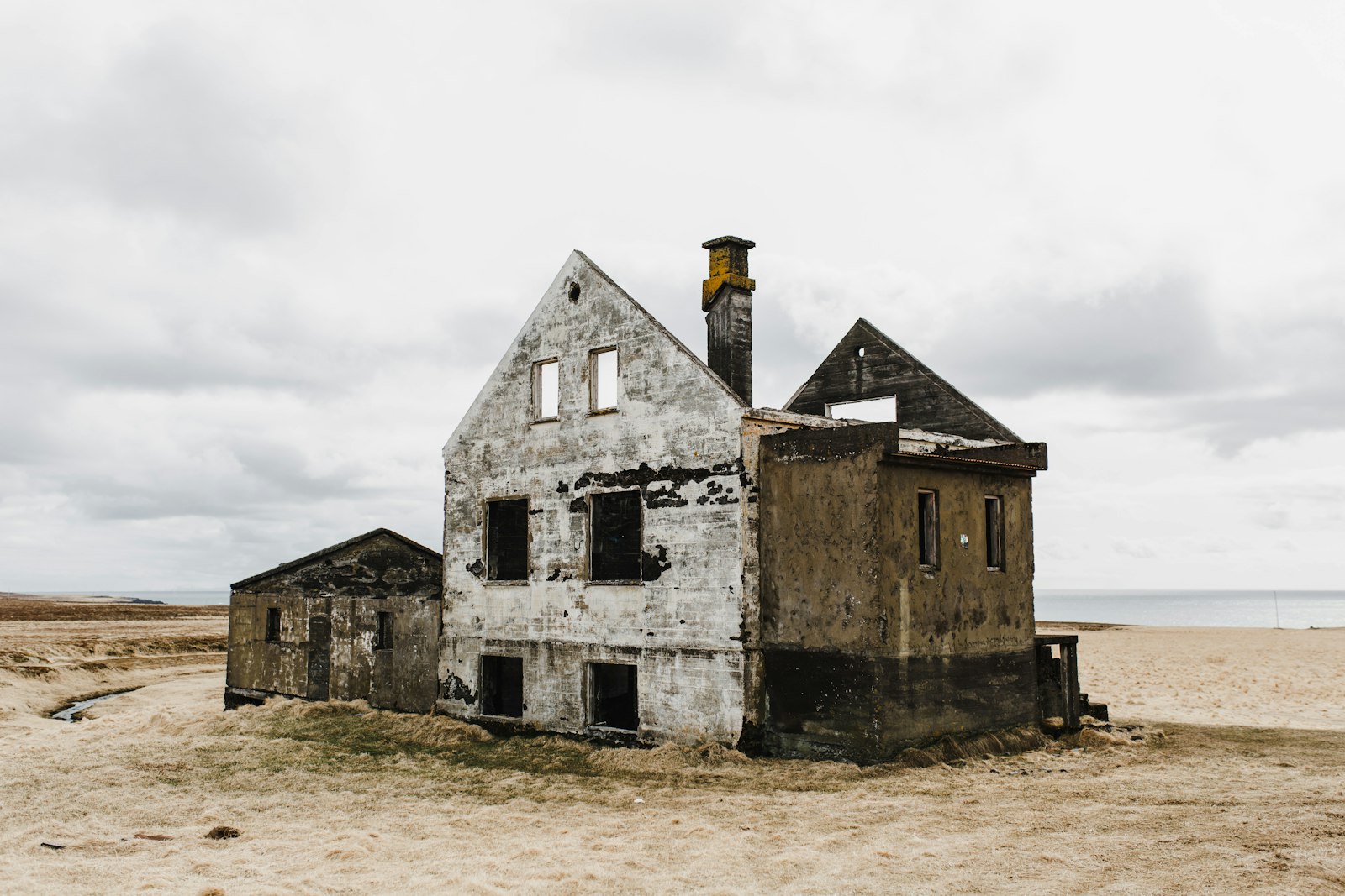 Casa abandonada de hormigón blanco y gris en una costa bajo nubes