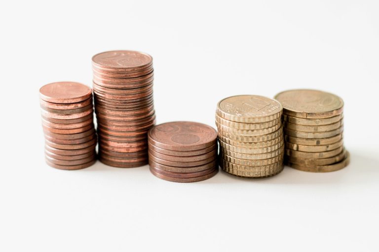 Pilas de monedas doradas sobre una superficie blanca